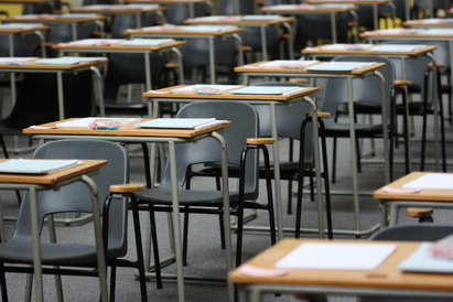 Exam desks and chairs arranged in a all with exam papers on the desks
